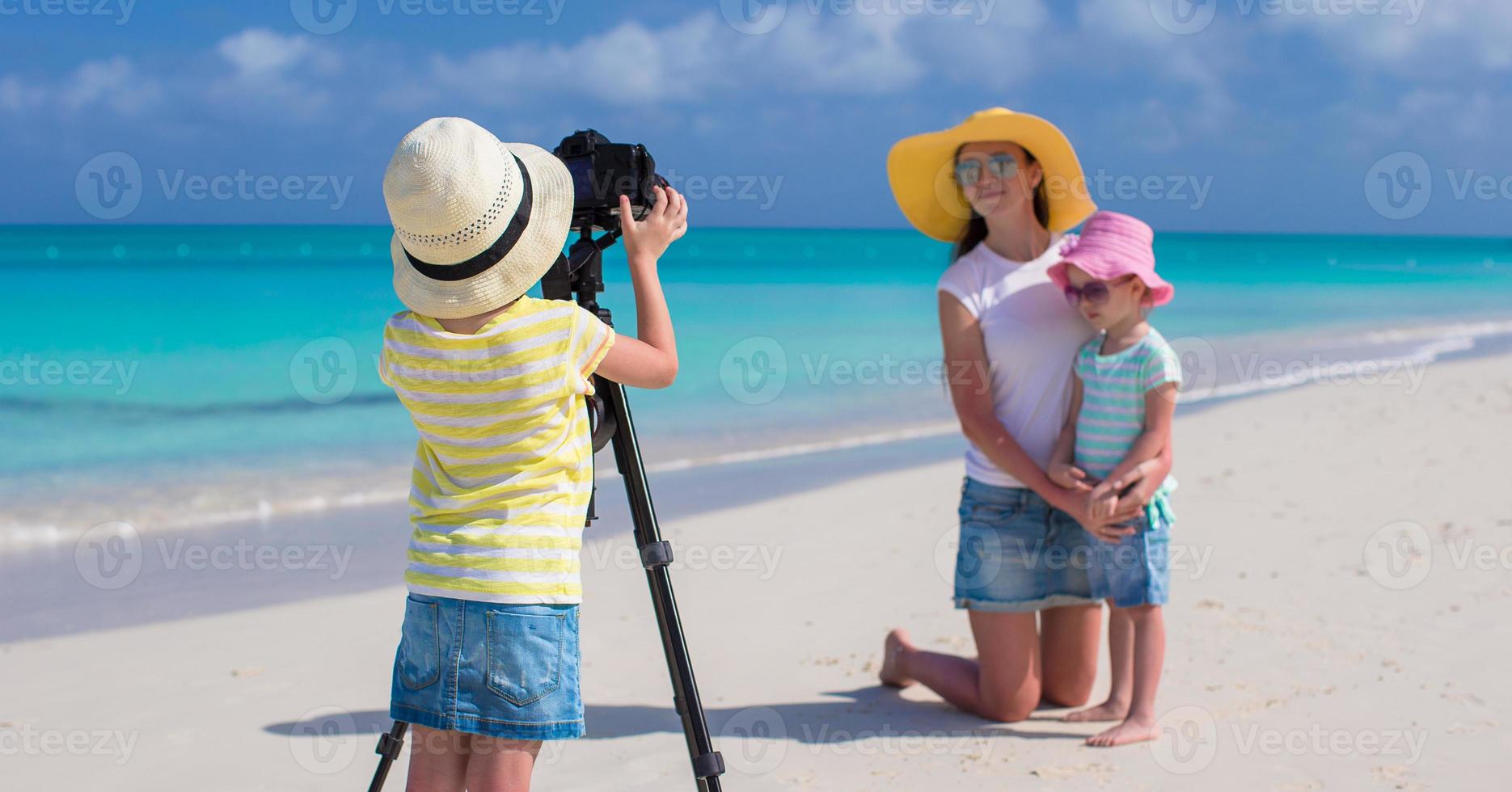 poco ragazza fabbricazione foto di sua mamma e sorella a il spiaggia