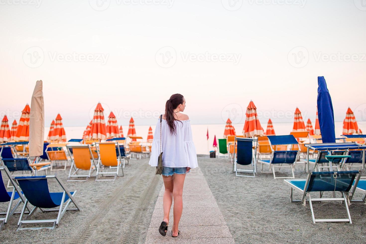 giovane donna su il spiaggia nel europeo vacanza su il ligure costa nel tramonto foto