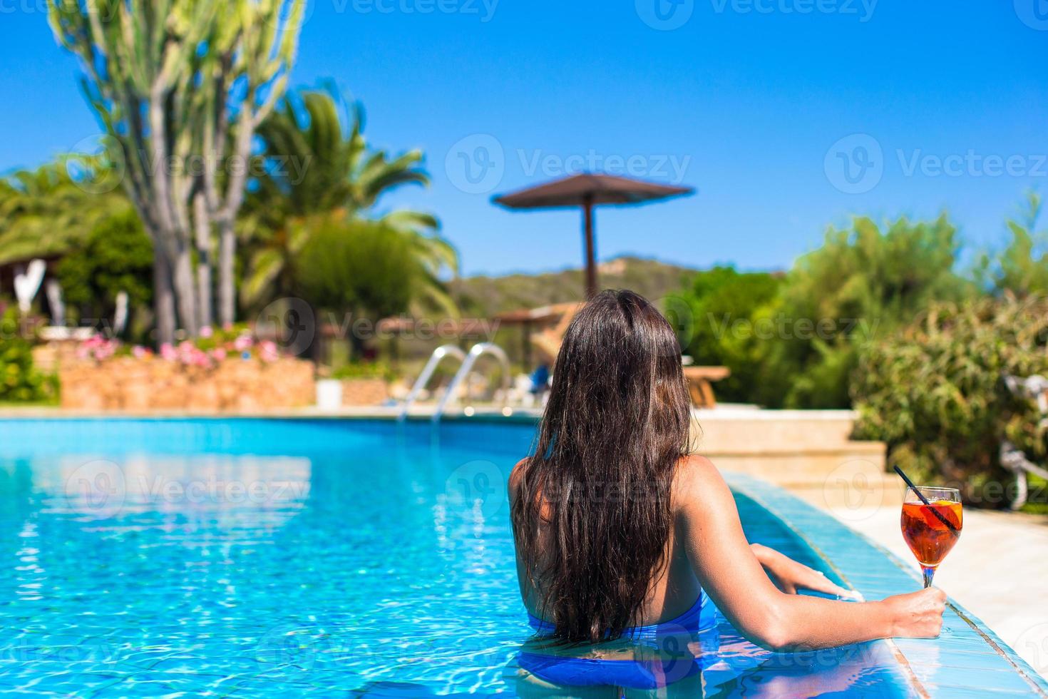 bellissimo giovane donna rilassante nel nuoto piscina con cocktail foto