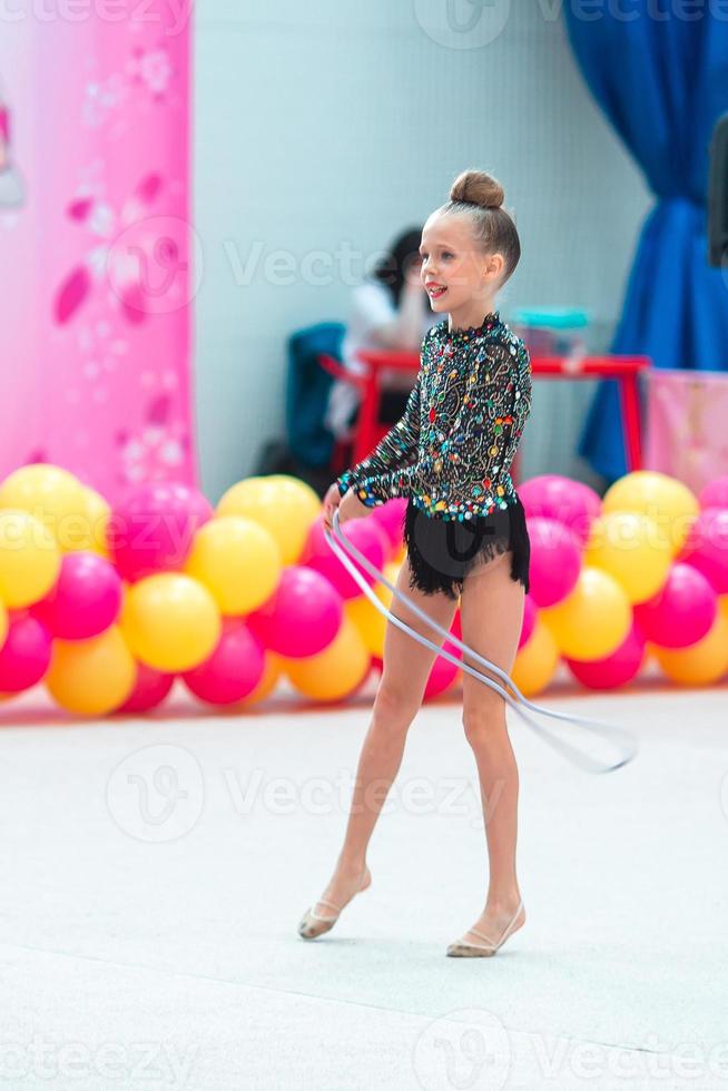 bellissimo poco ginnasta ragazza su il tappeto su il concorrenza foto