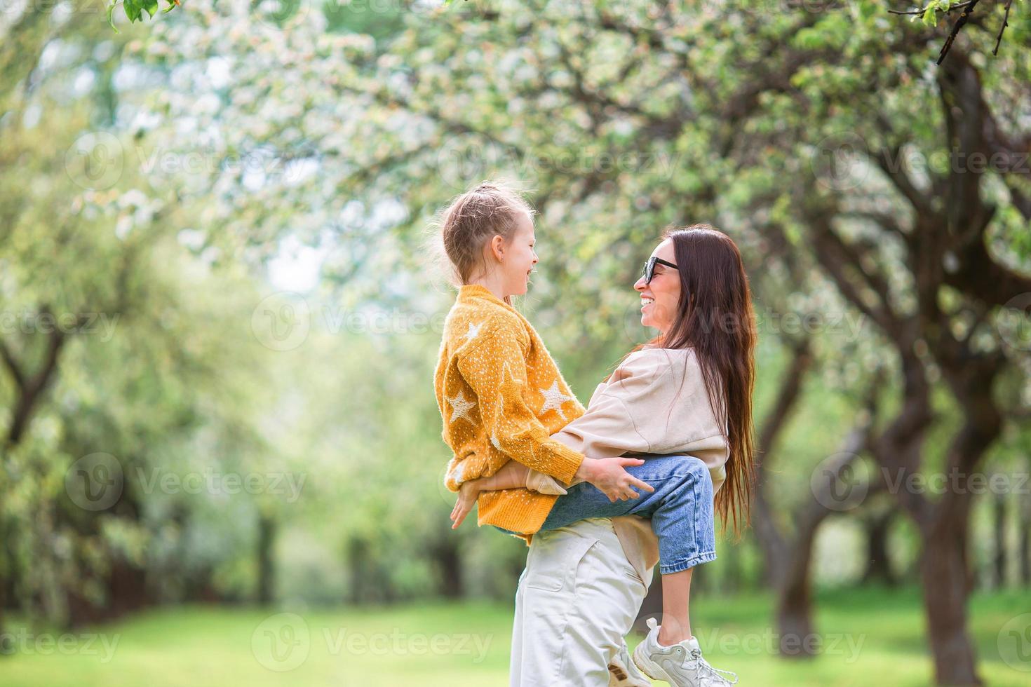 famiglia di madre e figlia nel fioritura ciliegia giardino foto