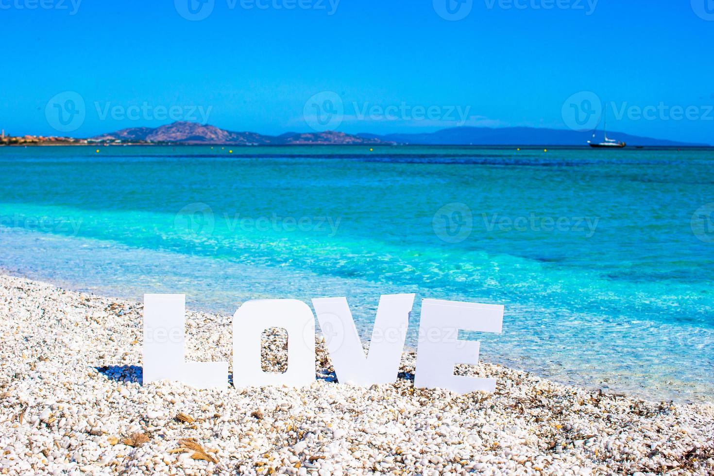 parola amore su tropicale spiaggia sfondo di turchese mare e blu cielo foto