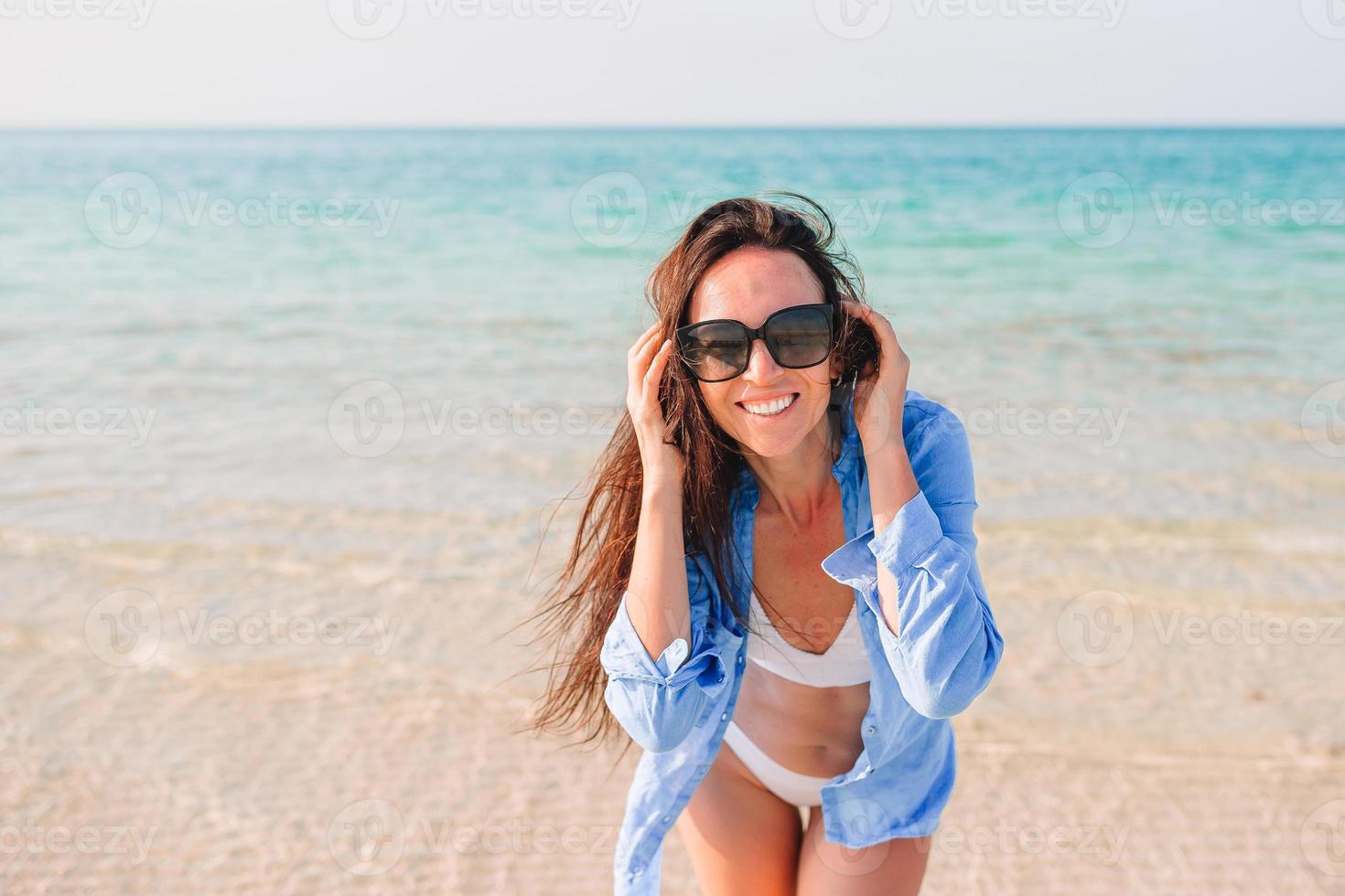 donna posa su il spiaggia godendo estate vacanze guardare a il mare foto