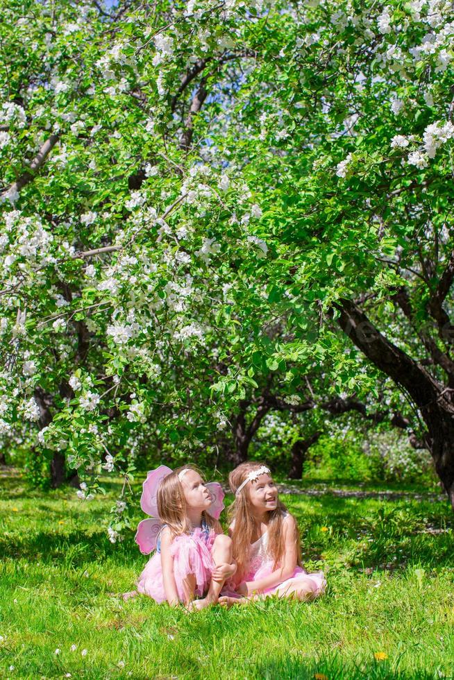 adorabile poco ragazze avere divertimento nel fioritura Mela albero giardino foto