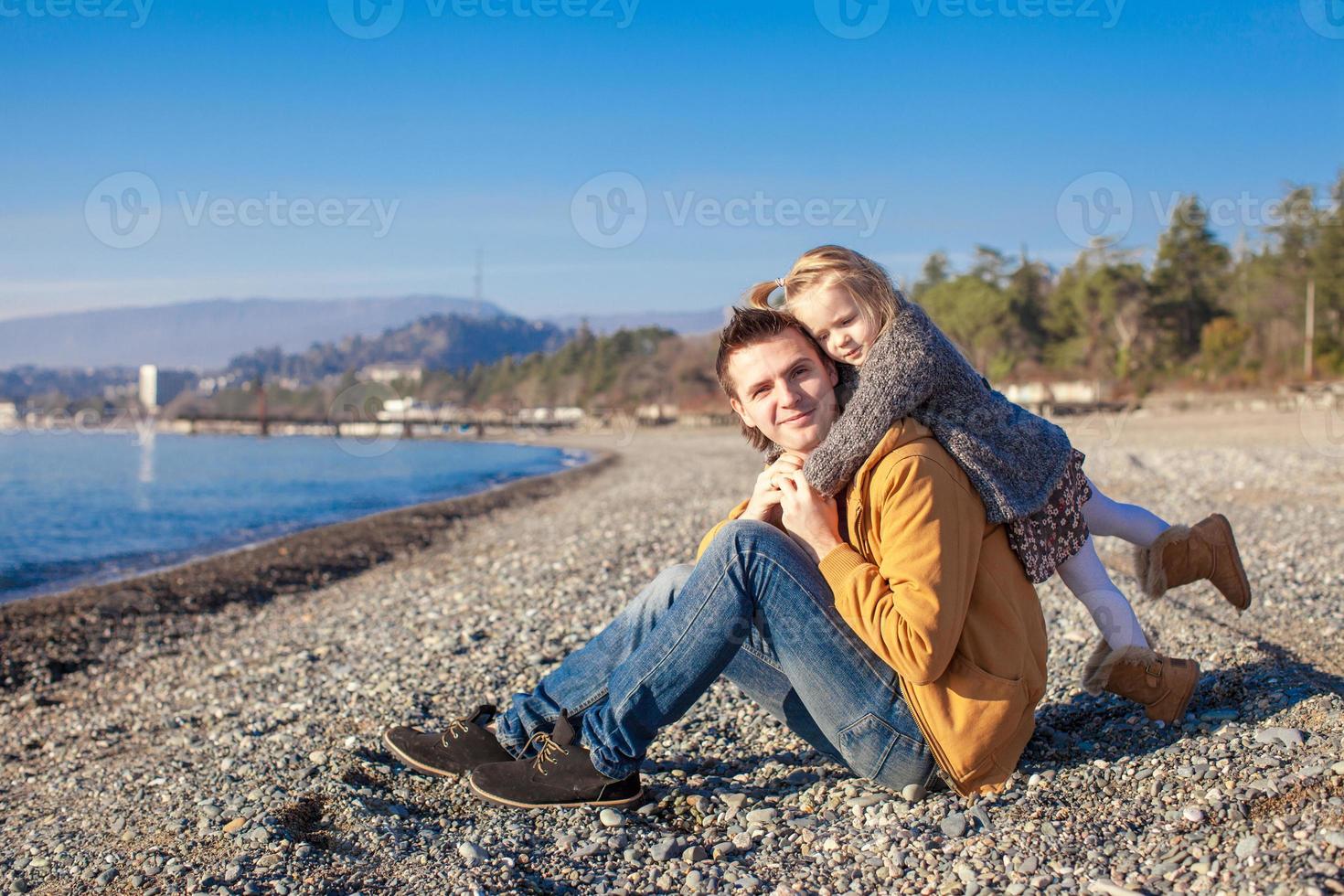 ritratto di un' adorabile ragazza abbracciare il suo giovane padre a il spiaggia foto