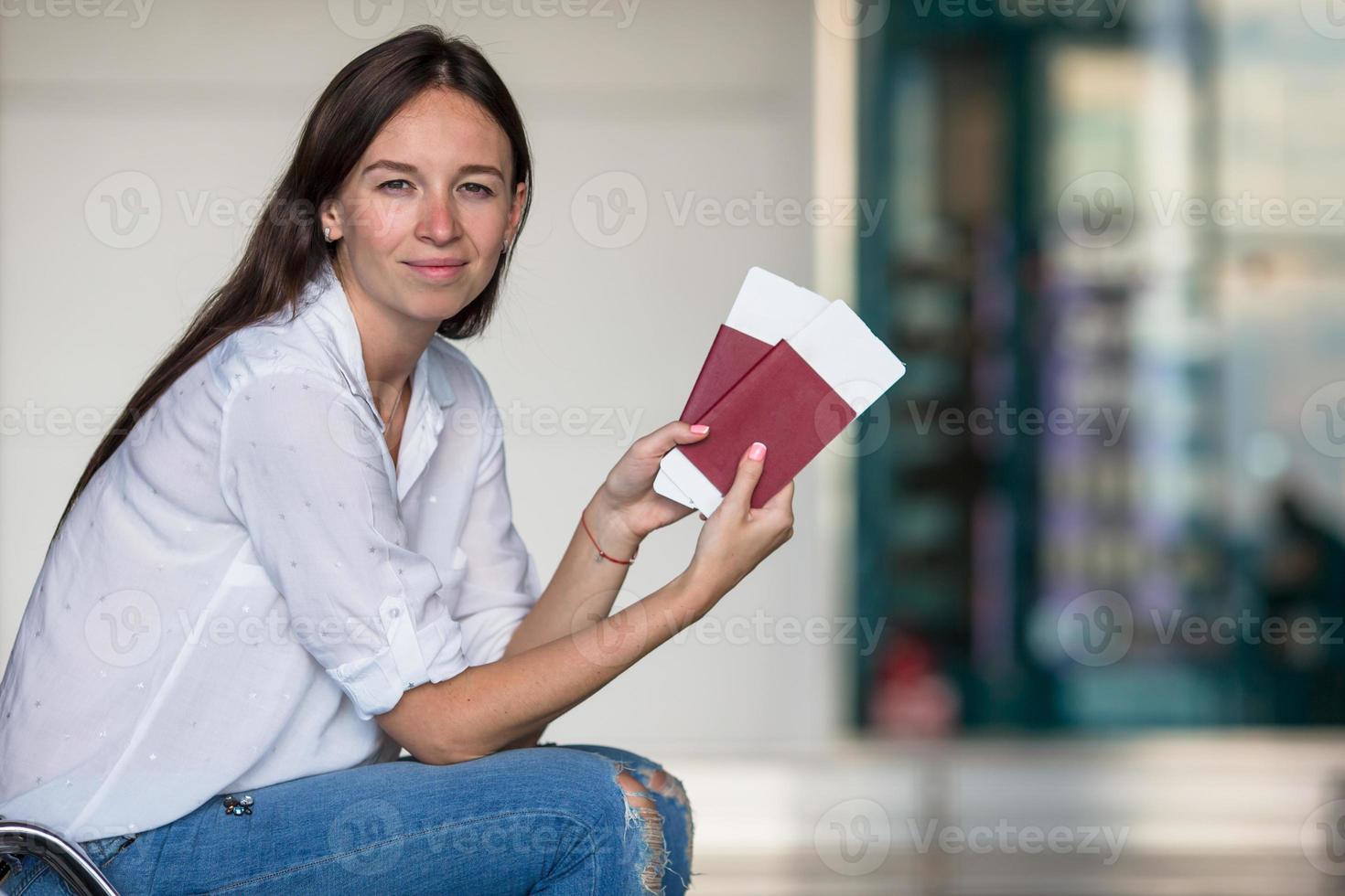 contento giovane donna con aria biglietto e passaporti a aeroporto in attesa per volo foto