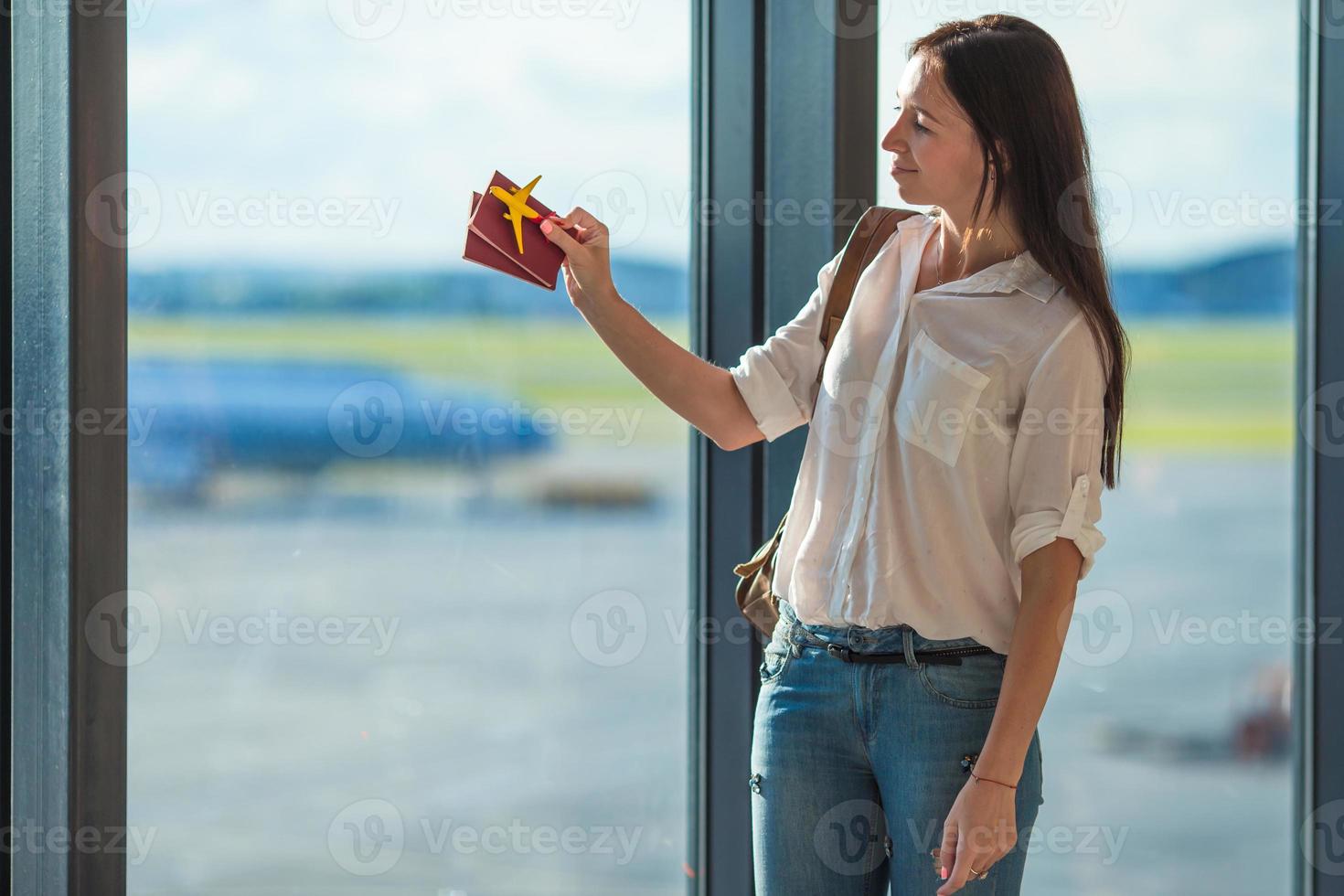 contento giovane donna con passaporti e aereo modello a aeroporto foto