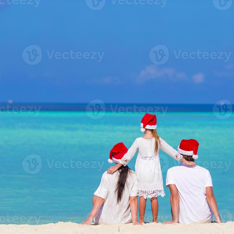 contento famiglia nel Santa cappelli su spiaggia durante Natale vacanza foto