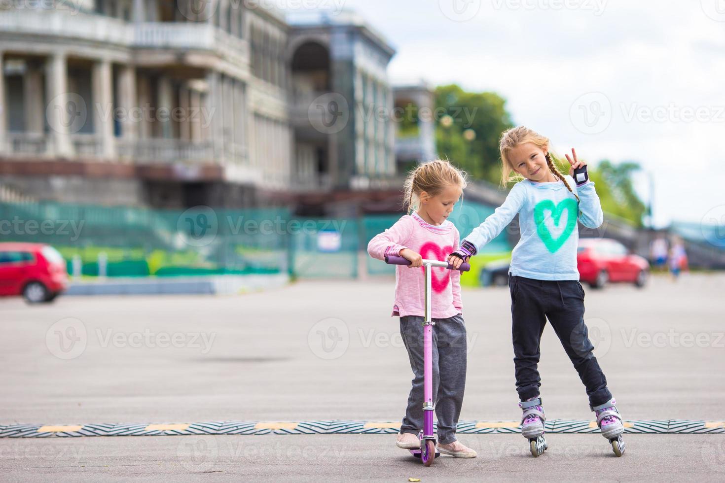Due poco ragazze rullo pattinando e equitazione un' scooter nel il parco all'aperto foto