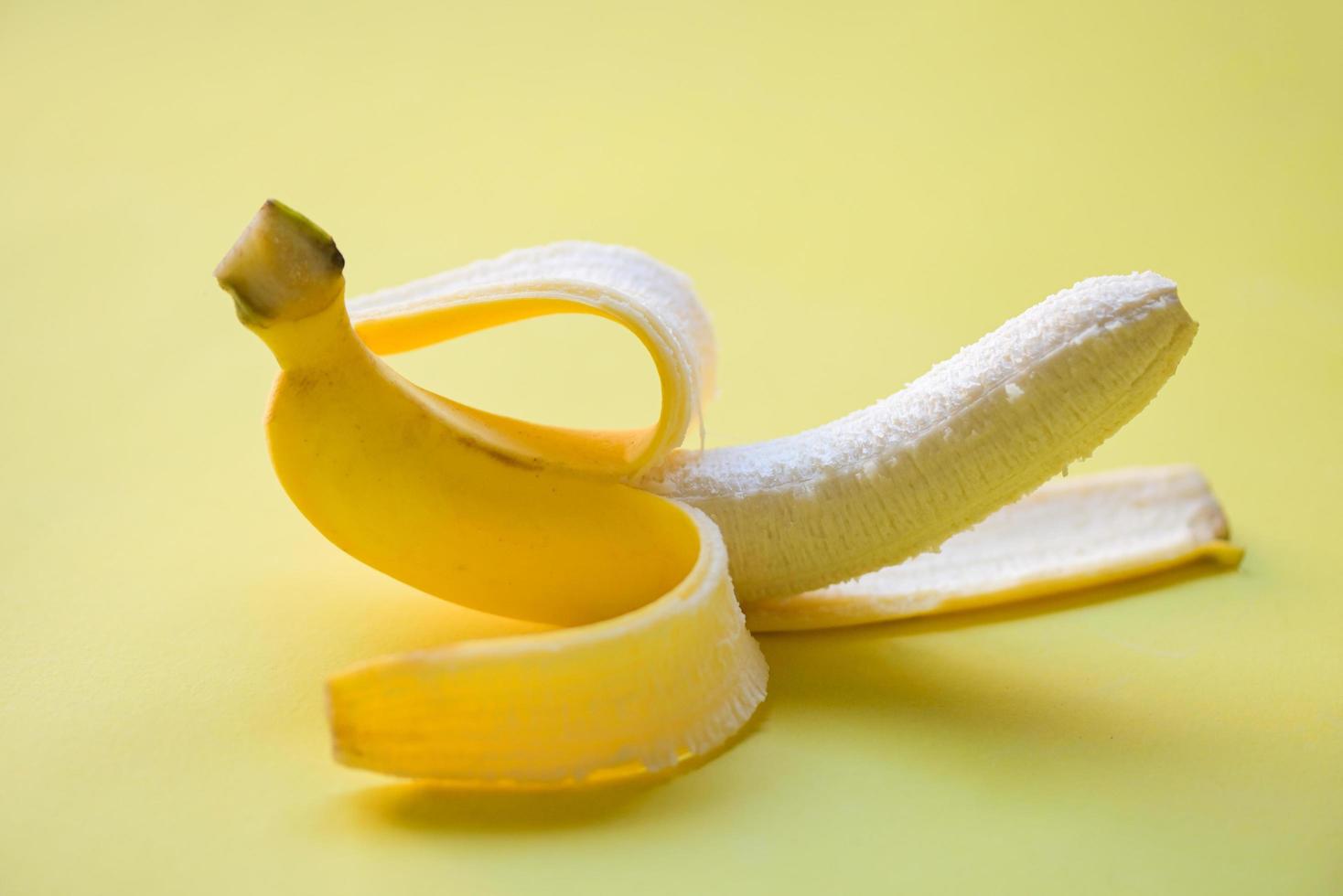 Banana sbucciare su giallo sfondo, maturo Banana sbucciare frutta su pavimento foto