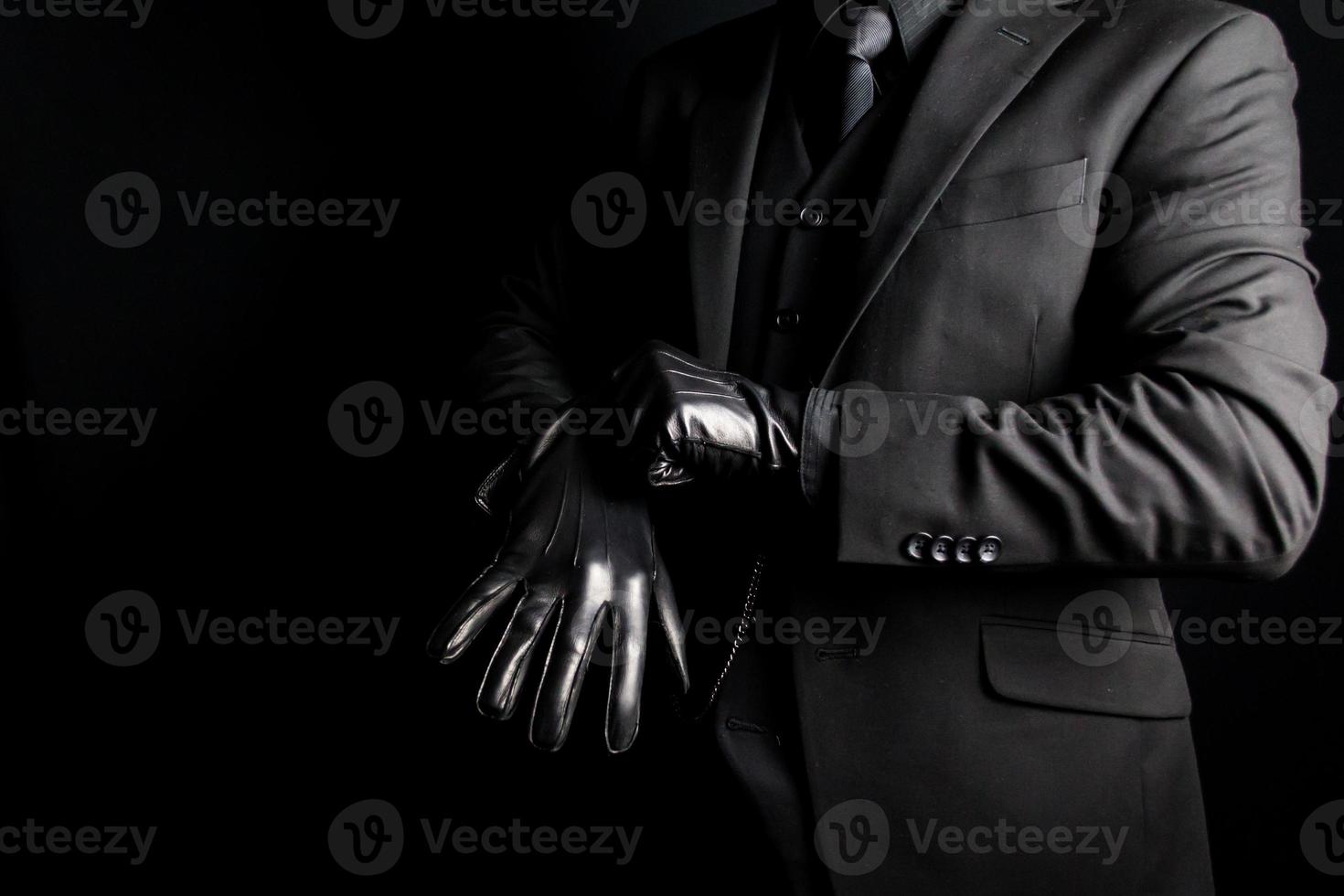 ritratto di uomo nel buio completo da uomo traino su pelle guanti su nero sfondo. concetto di gangster o mafia colpire uomo. foto