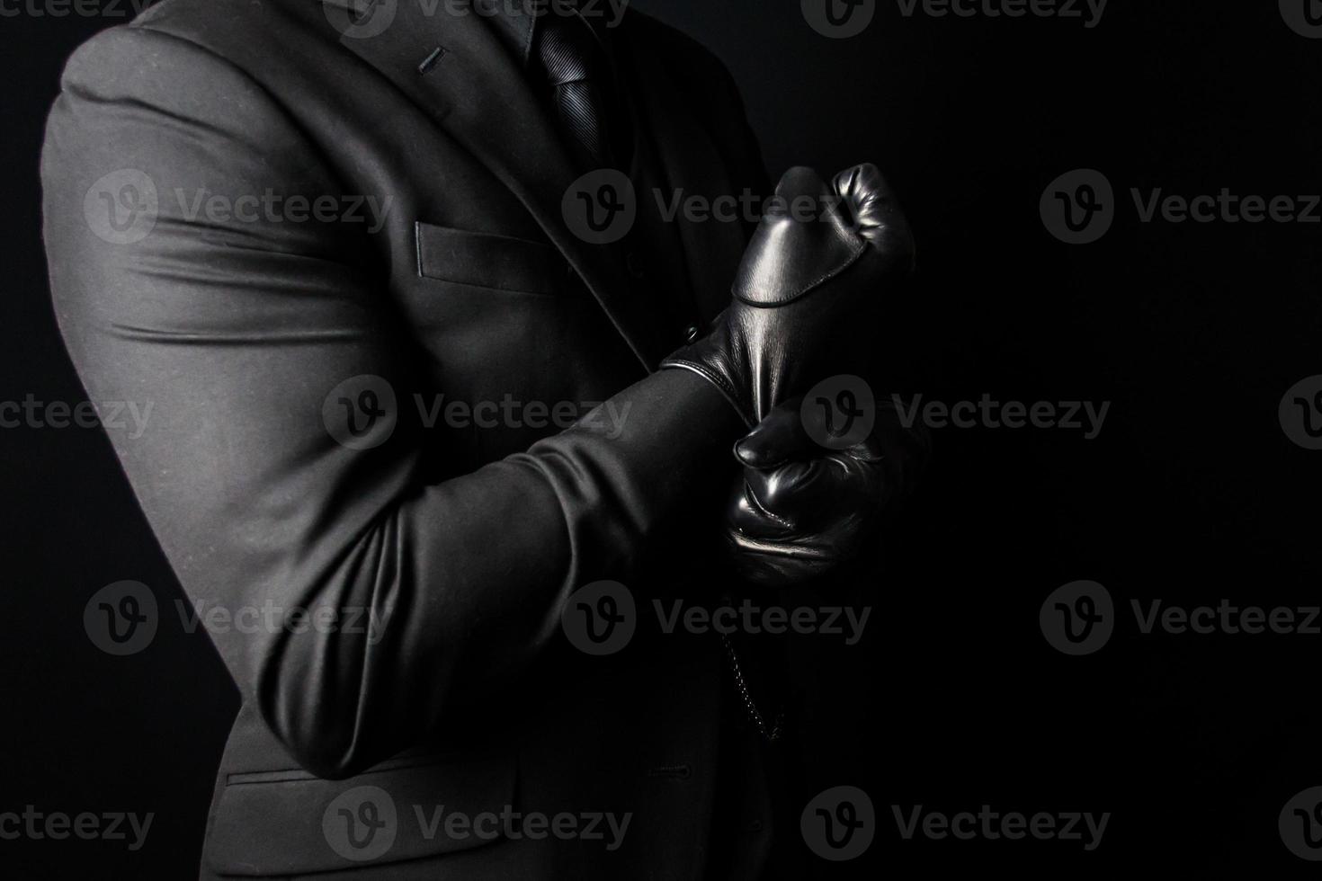 ritratto di forte uomo nel buio completo da uomo traino su nero pelle guanti. concetto di mafia sicario o signore assassino foto