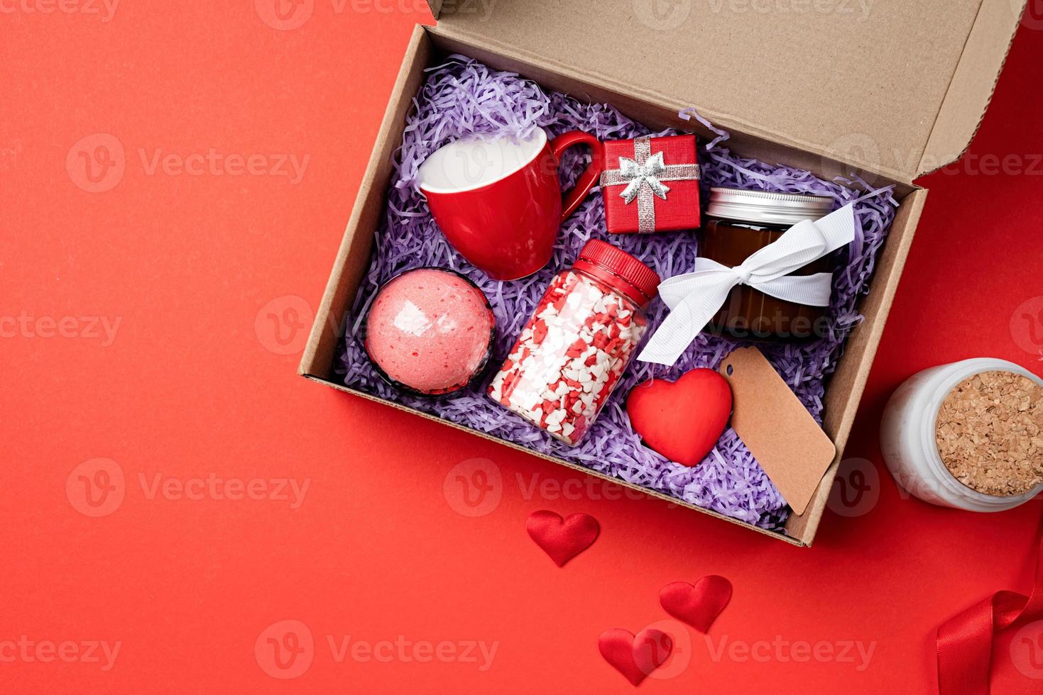 di stagione regalo scatola per San Valentino giorno con candela, rosso tazza e cuore forma dolci su rosso sfondo foto