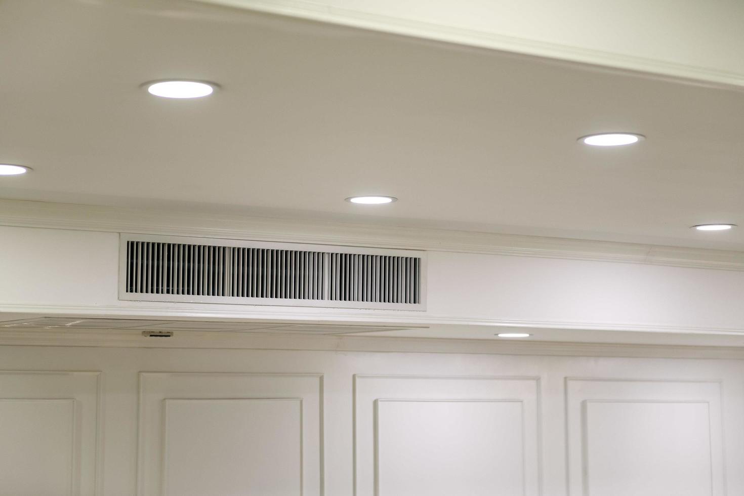 soffitto montato cassetta genere aria condizionatore e moderno lampada leggero su bianca soffitto. condotto aria condizionatore per casa o ufficio foto