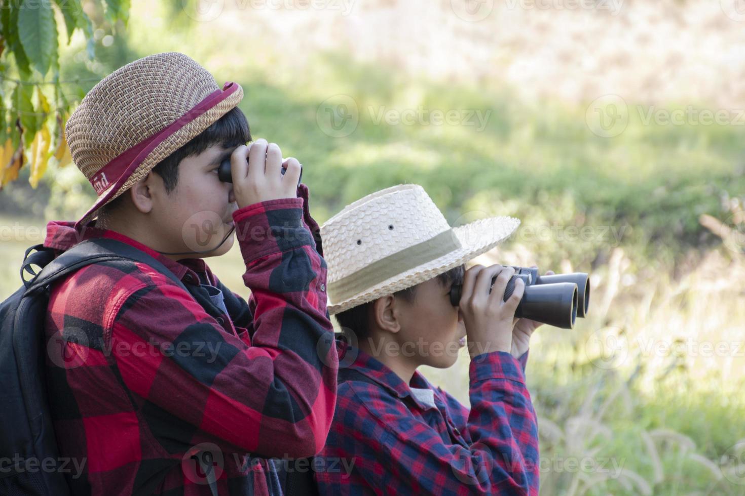 asiatico ragazzi siamo utilizzando binocolo per fare il uccelli' Guardando nel tropicale foresta durante estate campo, idea per apprendimento creature e natura animali e insetti al di fuori il aula. foto