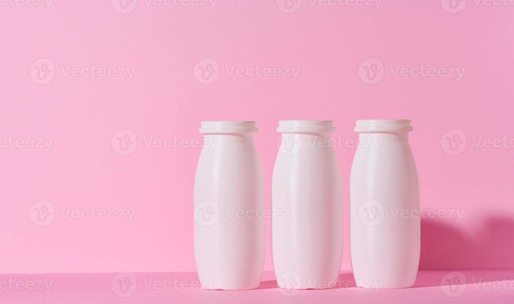 bianca plastica bottiglie per Yogurt e latteria prodotti su un' rosa sfondo foto