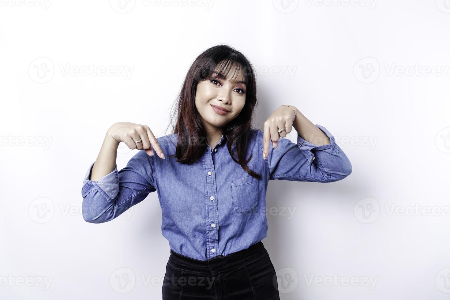 eccitato asiatico donna indossare blu camicia puntamento giù a il copia spazio, isolato di bianca sfondo foto
