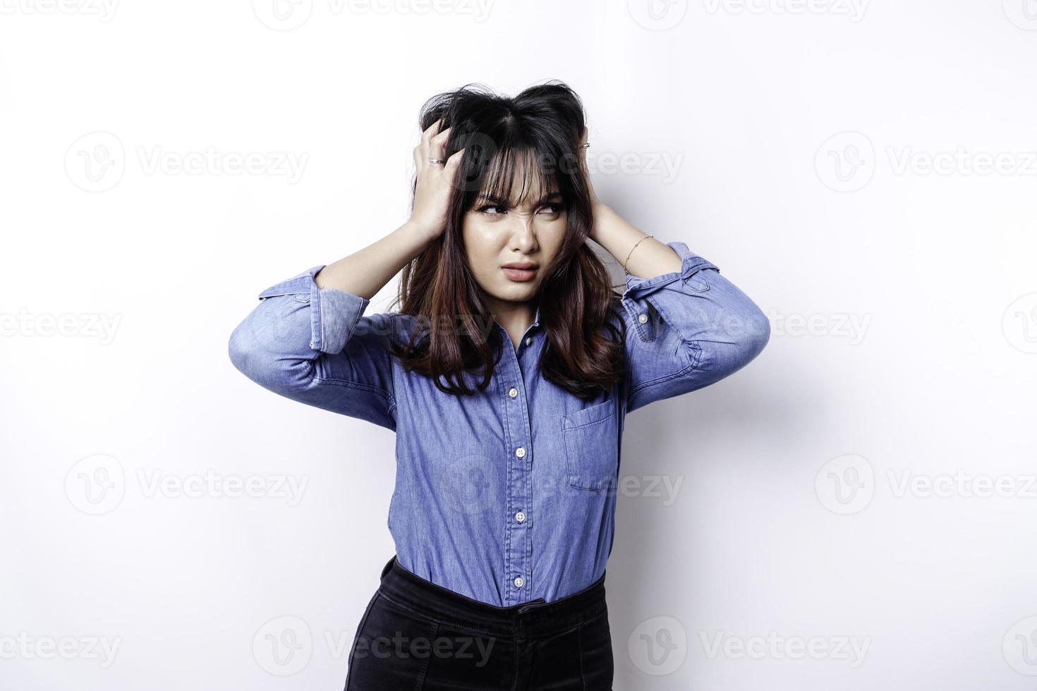 un' ritratto di un asiatico donna indossare un' blu camicia isolato di bianca sfondo sembra depresso foto