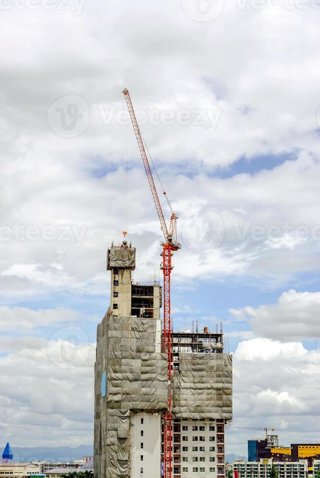 sollevamento gru Lavorando edificio costruzione su luminosa blu cielo e grande nube sfondo. foto