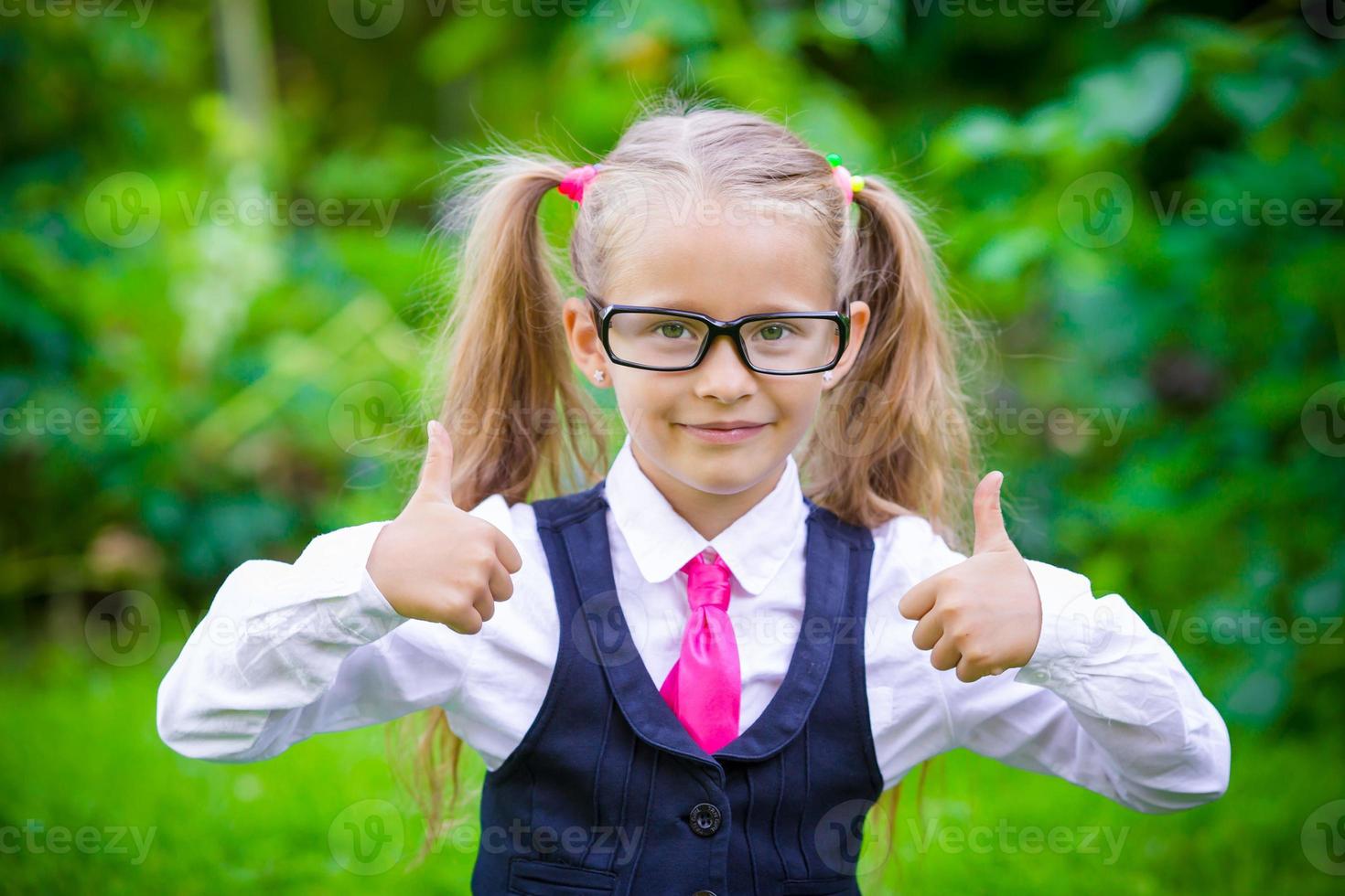 poco contento ragazza mostrando pollici su. indietro per scuola all'aperto foto