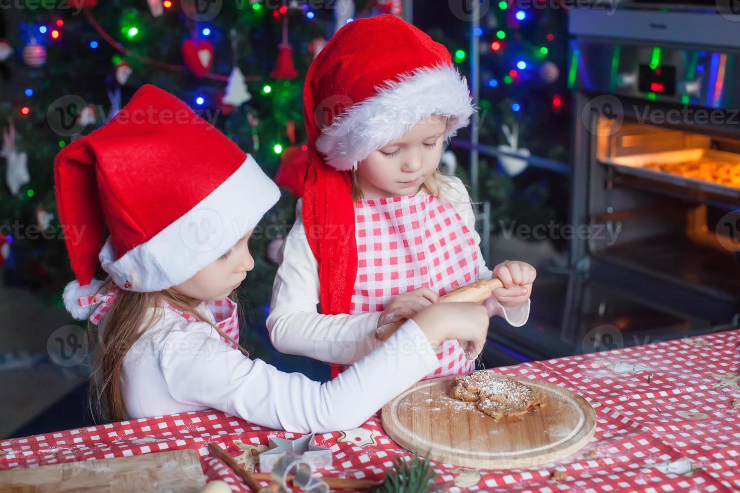 poco ragazze nel Santa cappelli cottura al forno Natale Pan di zenzero biscotti foto