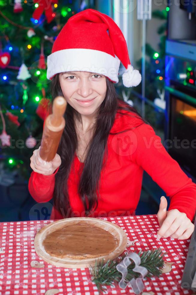 giovane donna nel Natale cappello cottura al forno Pan di zenzero a casa foto