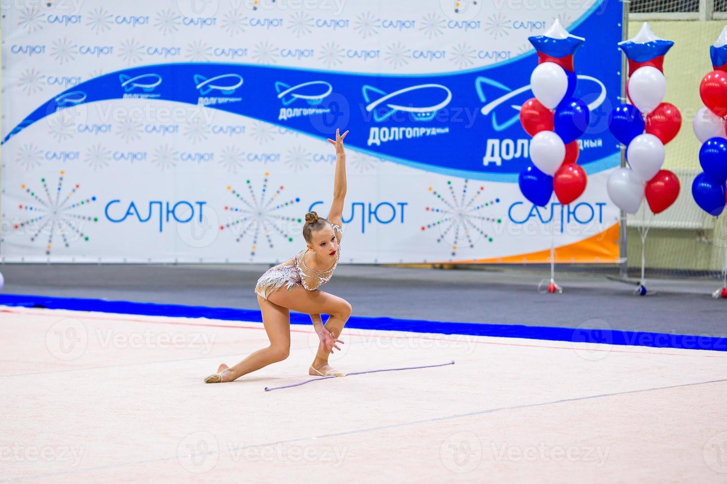 bellissimo poco attivo ginnasta ragazza con sua prestazione su il tappeto foto