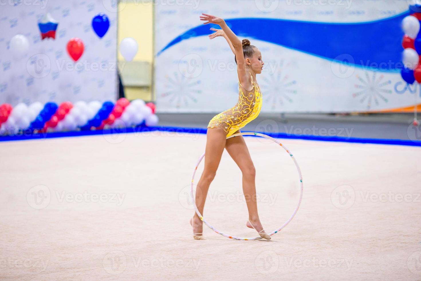 bellissimo poco ginnasta ragazza su il tappeto su il concorrenza foto