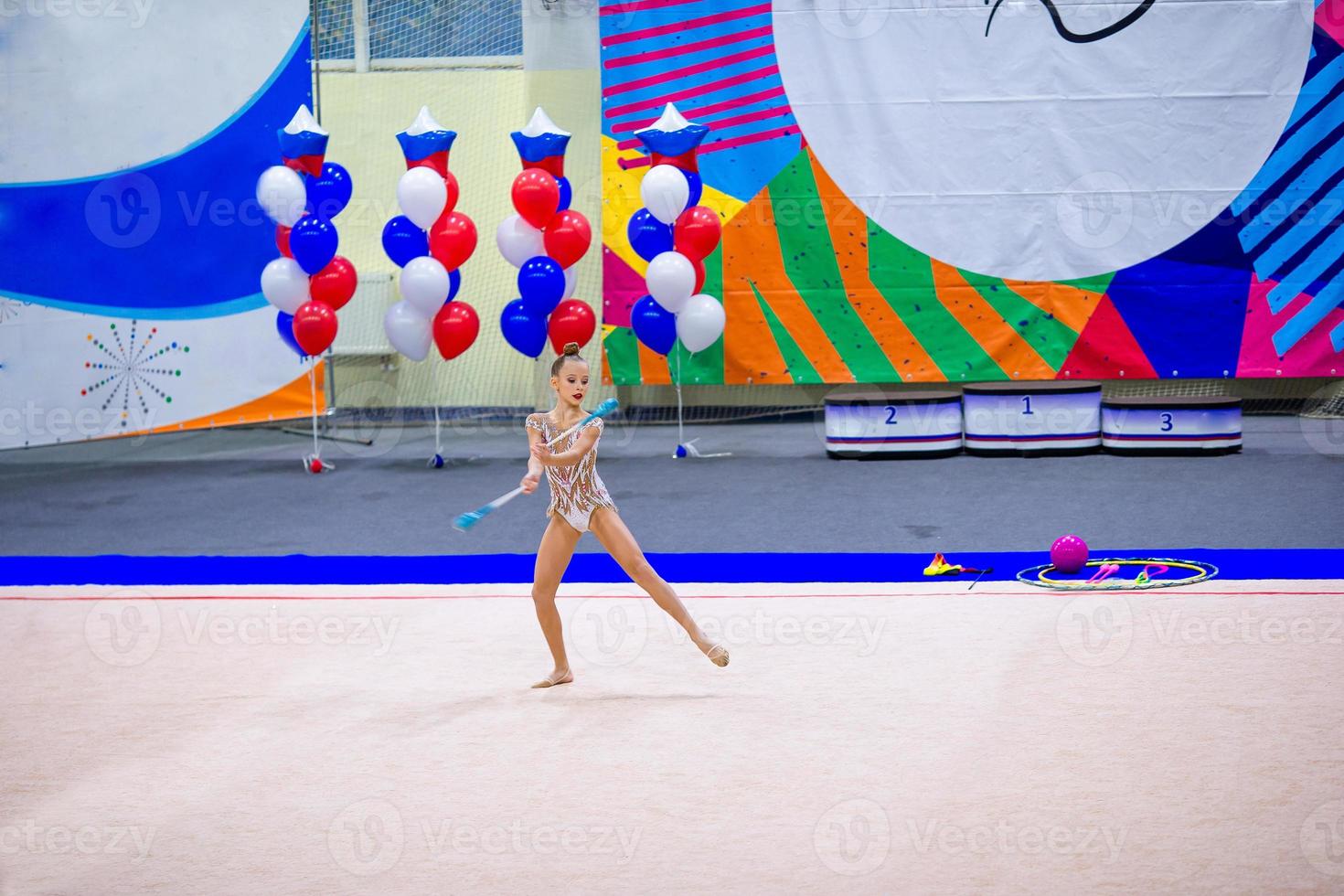 bellissimo poco attivo ginnasta ragazza con sua prestazione su il tappeto foto