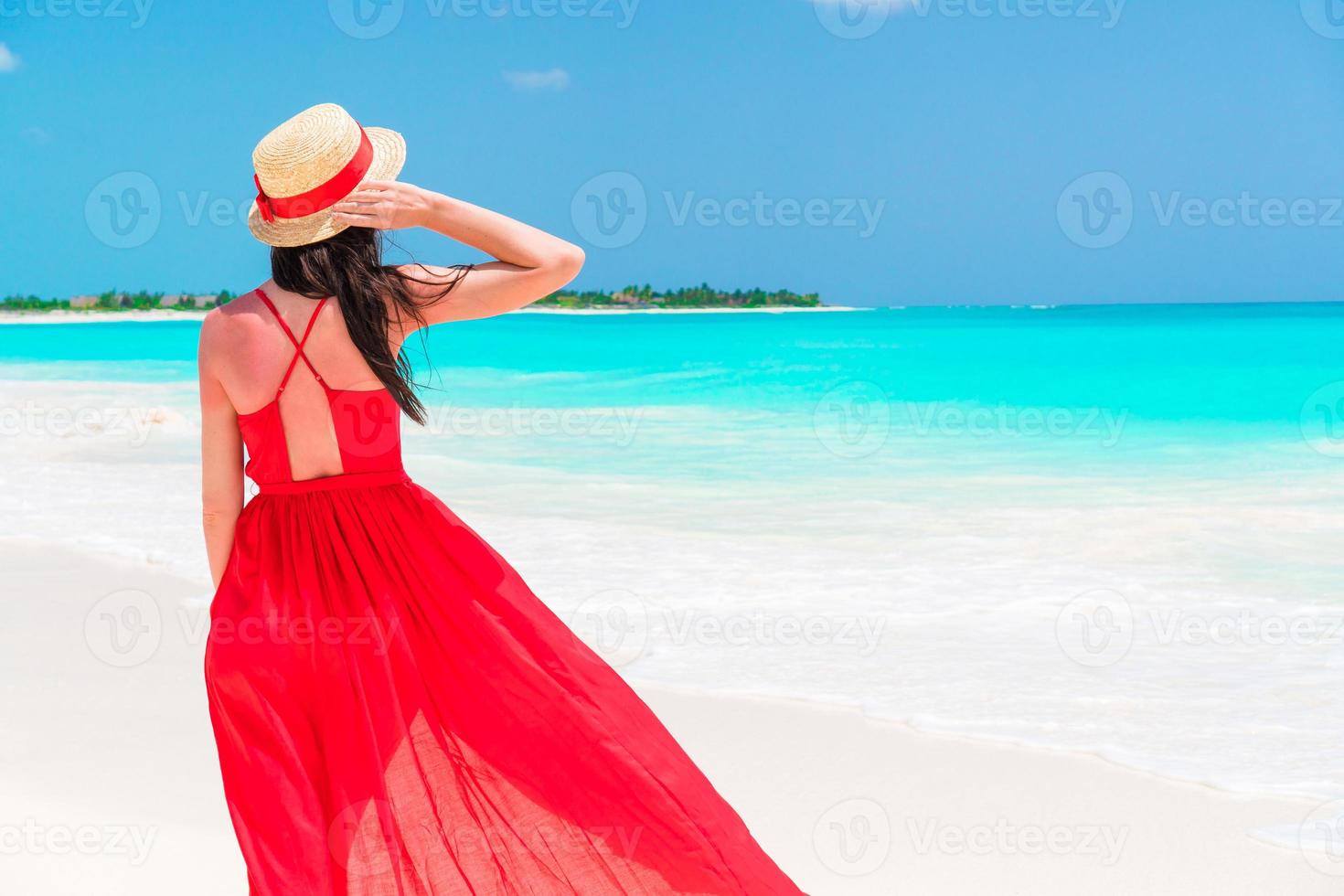 bellissimo donna su tropicale spiaggia. giovane ragazza nel bellissimo rosso vestito sfondo il mare foto