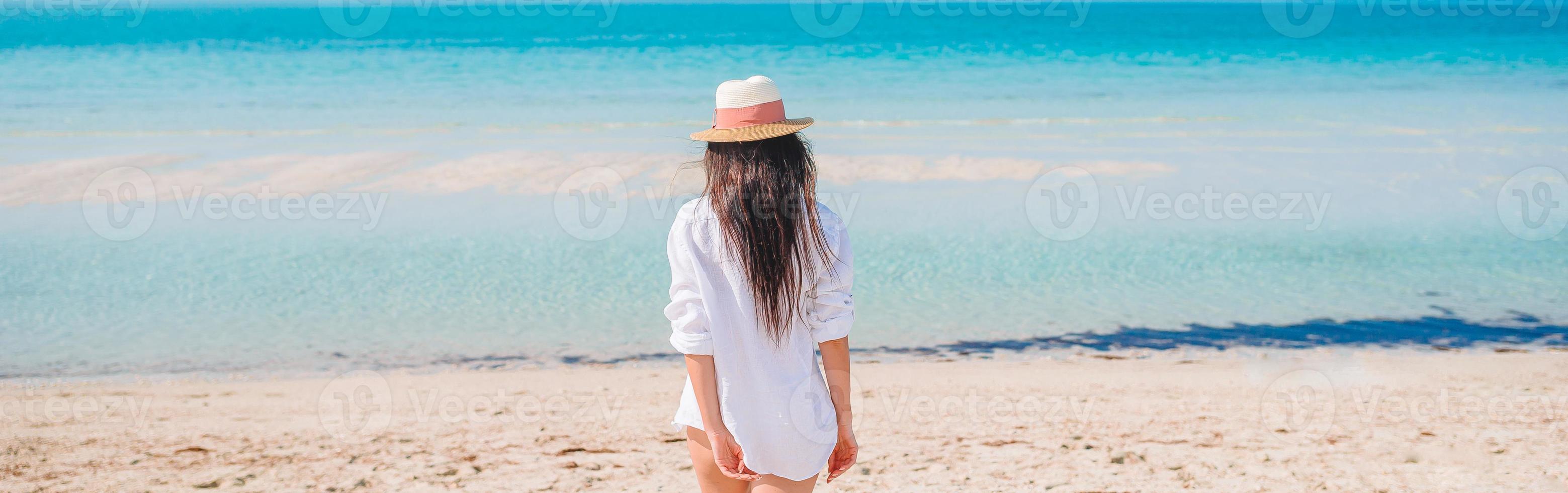 donna posa su il spiaggia godendo estate vacanze guardare a il mare foto