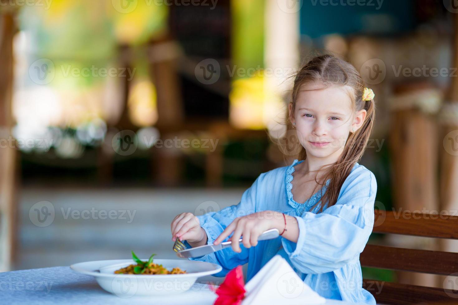 adorabile poco ragazza avendo pranzo a all'aperto bar foto