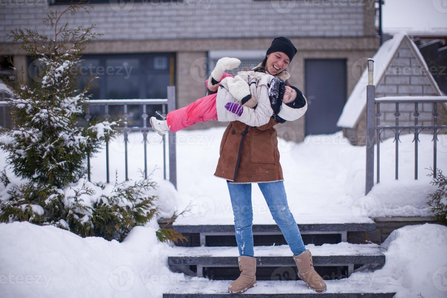 contento giovane madre con sua poco figlia avendo divertimento nel il Giardino dietro la casa su un' inverno giorno foto