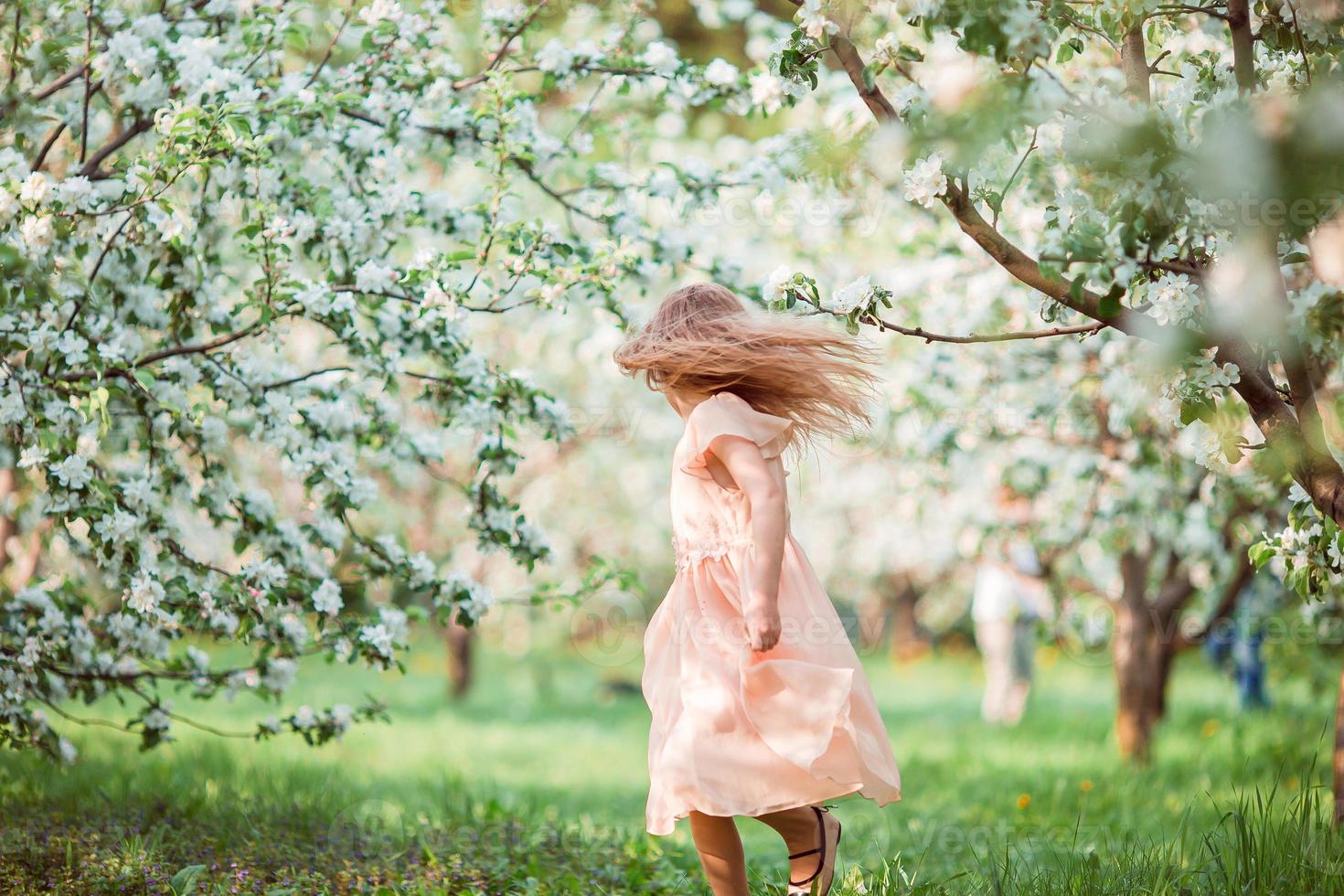 carino ragazza nel fioritura Mela albero giardino godere il caldo giorno foto