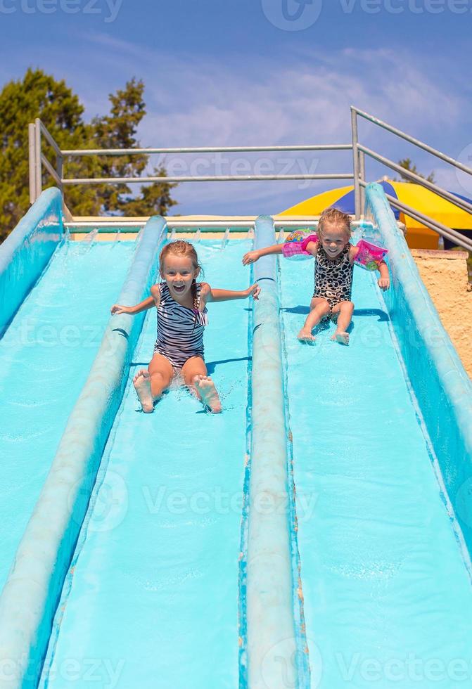 carino ragazze su acqua diapositiva a Parco acquatico durante estate vacanza foto