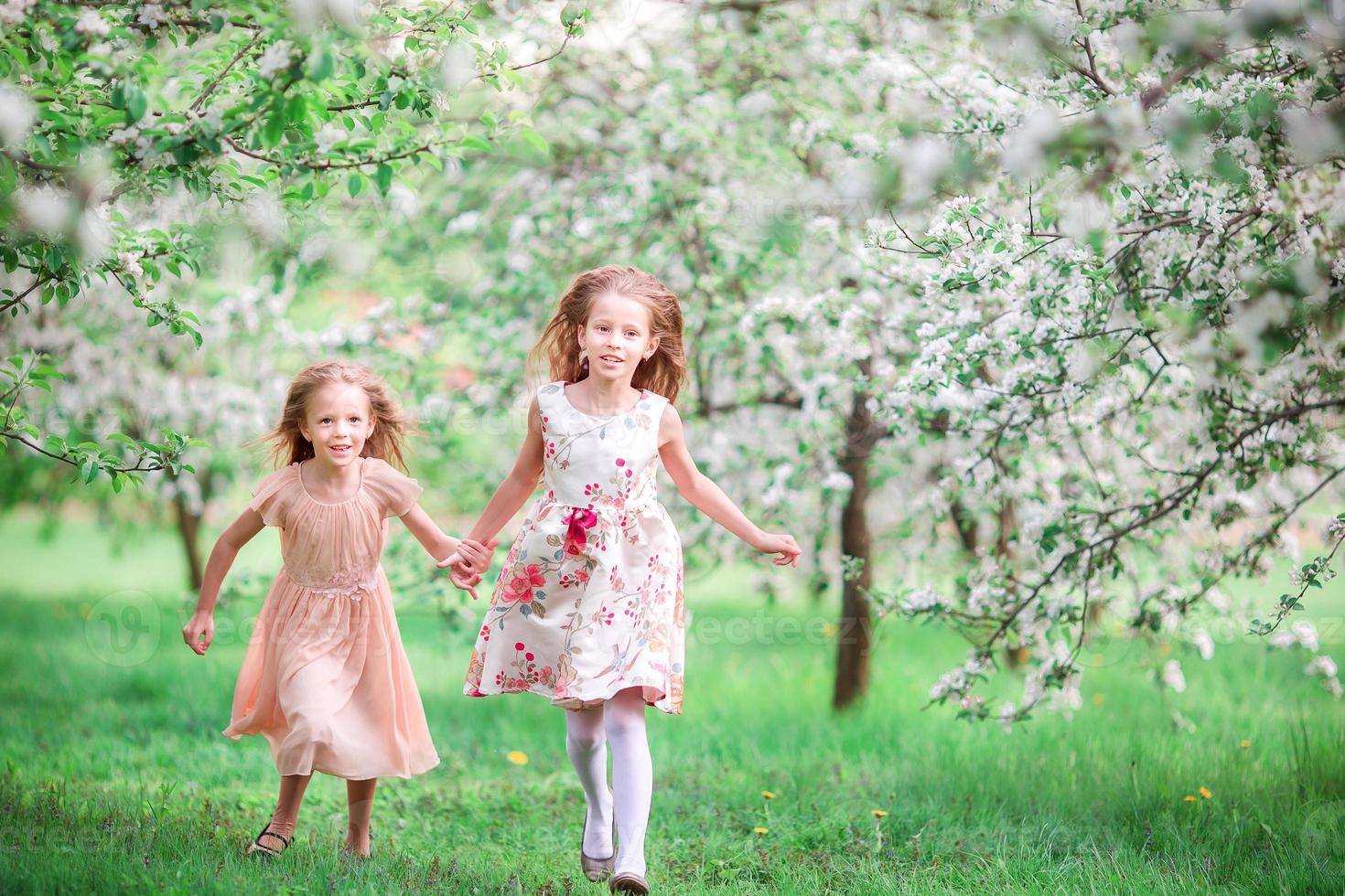 adorabile poco ragazze nel fioritura ciliegia albero giardino su primavera giorno foto