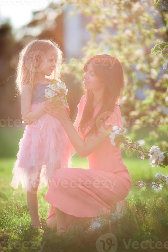 adorabile poco ragazza con giovane madre nel fioritura ciliegia giardino su bellissimo primavera giorno foto