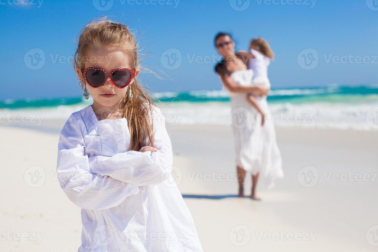 ritratto di carino ragazza e sua madre con poco sorella nel il sfondo a tropicale spiaggia foto