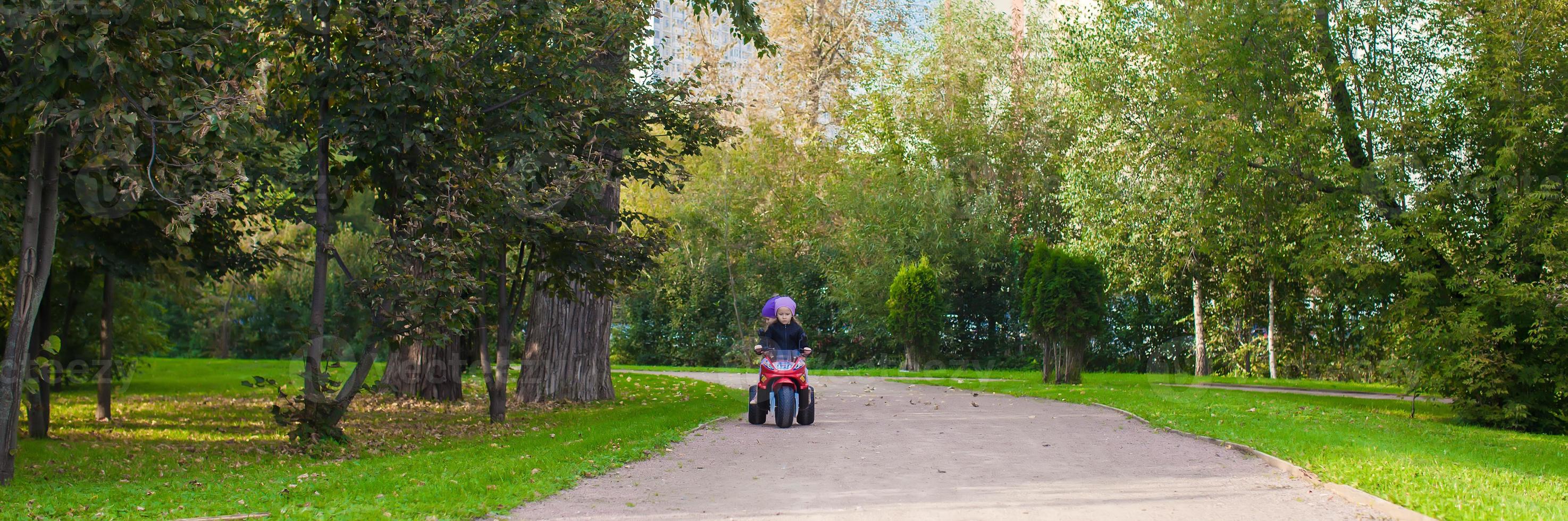 adorabile poco ragazze equitazione su capretto motobike nel il verde parco foto