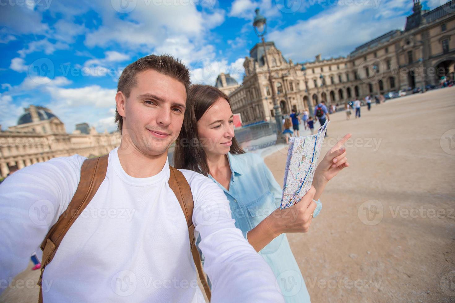 contento giovane famiglia con carta geografica di europeo città assunzione autoscatto nel Parigi foto