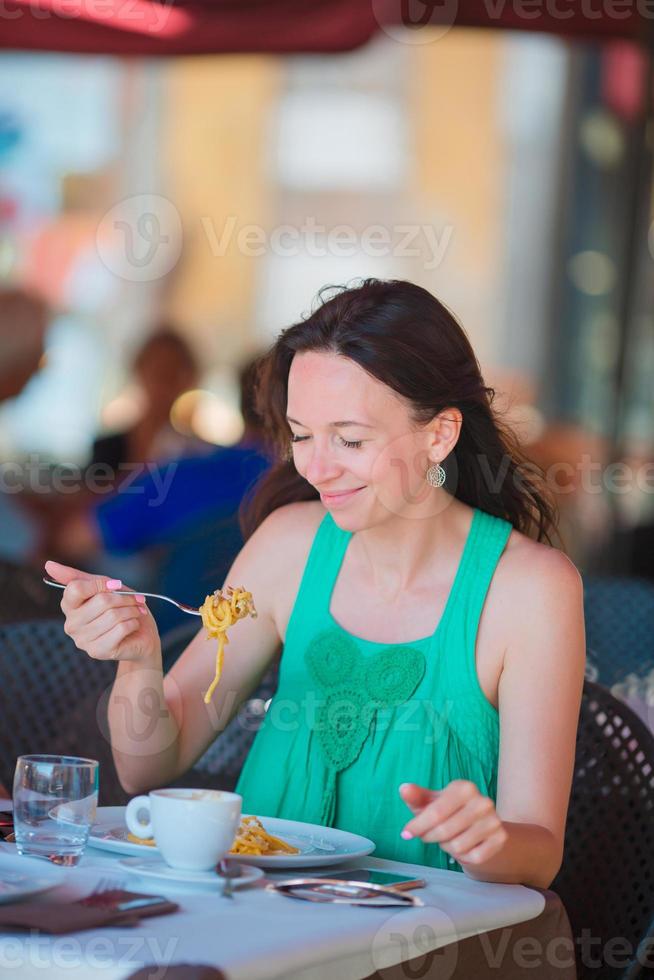 giovane donna mangiare spaghetti a all'aperto bar su italiano vacanza foto