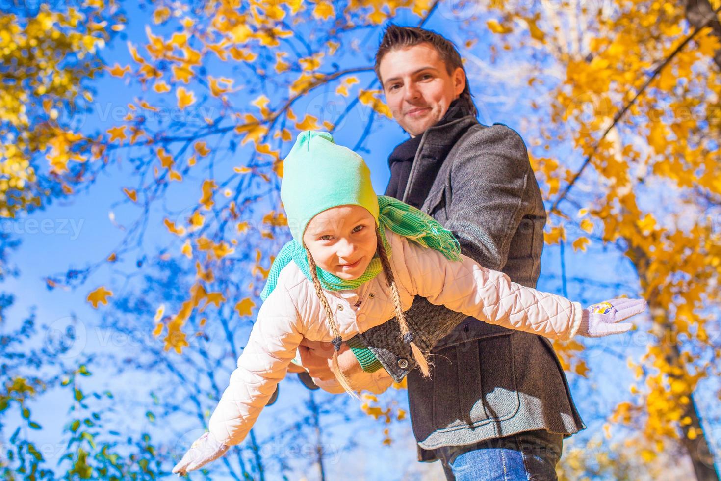 poco carino ragazza con contento padre avendo divertimento nel autunno parco su un' soleggiato giorno foto