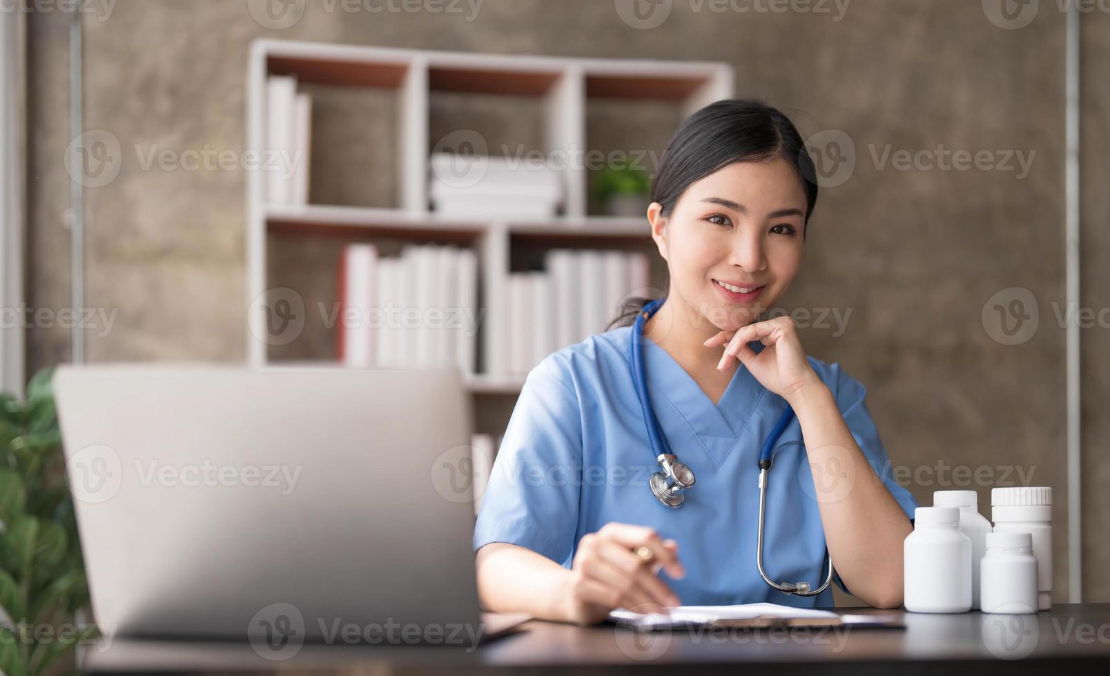 asiatico medico giovane bellissimo donna sorridente utilizzando Lavorando con un' il computer portatile computer e sua scrittura qualcosa su lavoro d'ufficio o appunti bianca carta a ospedale scrivania ufficio, assistenza sanitaria medico concetto foto