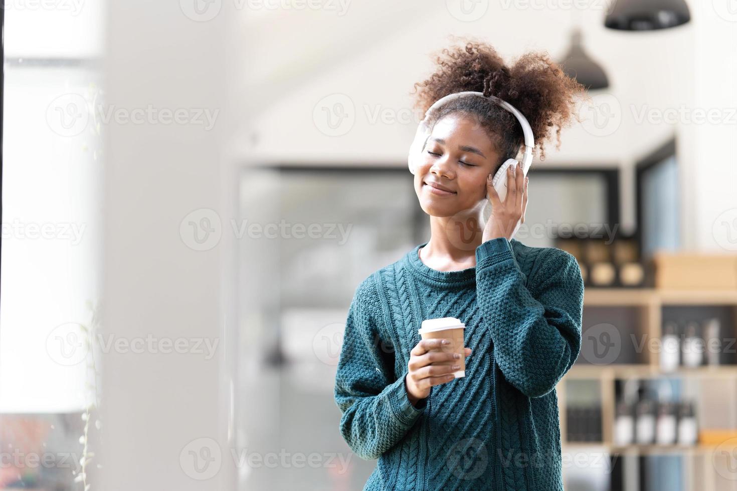 ritratto di sorridente giovane nero donna ascoltando musica con cuffia e digitale tavoletta foto