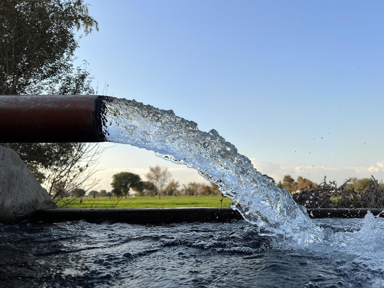 irrigazione acqua flusso a partire dal tubo per canale per agricoltura i campi foto