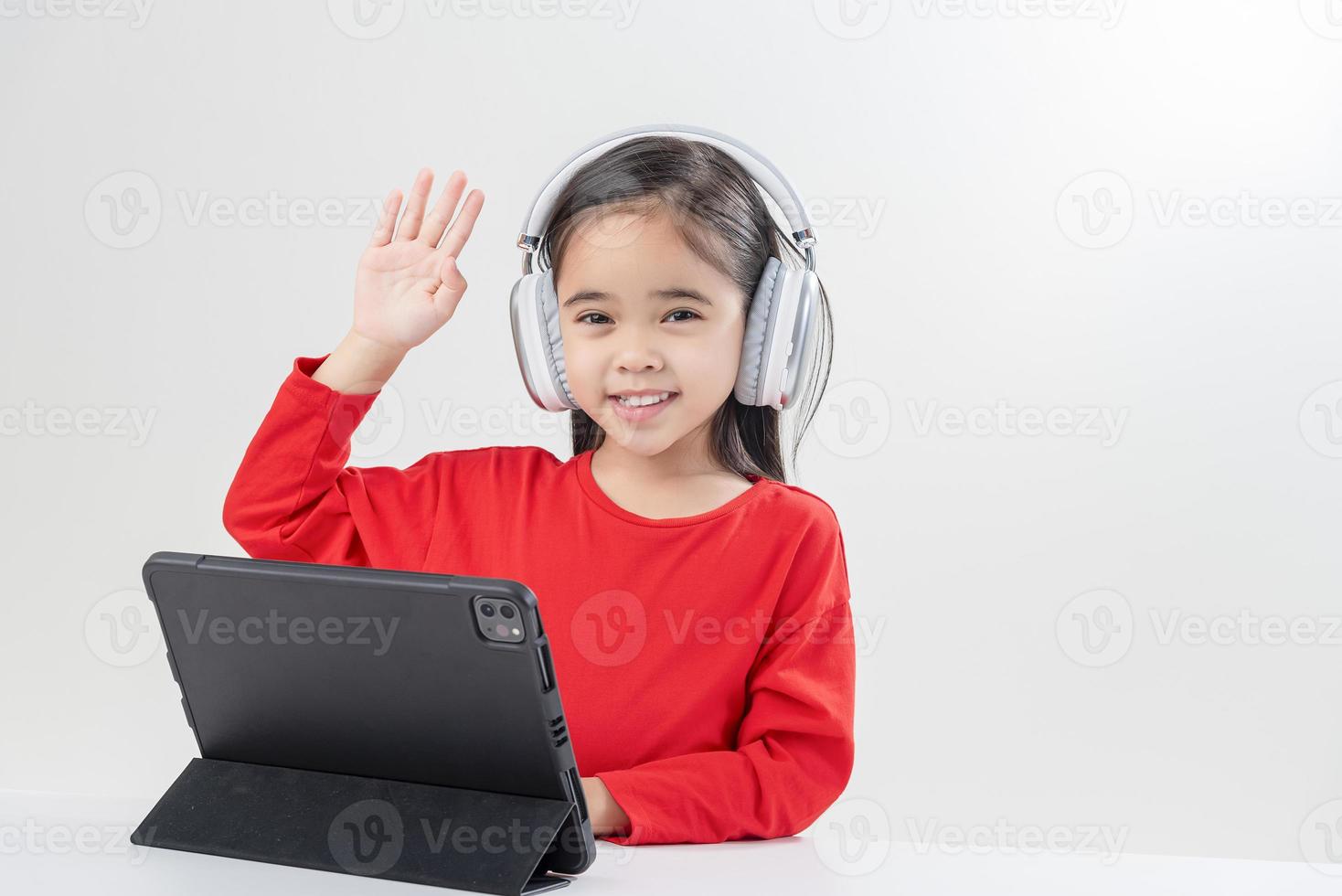 poco ragazza Asia carino mettere su cuffie avere video chiamata lontano classe con insegnante utilizzando computer portatile, studia in linea su computer, homeschooling concetto foto