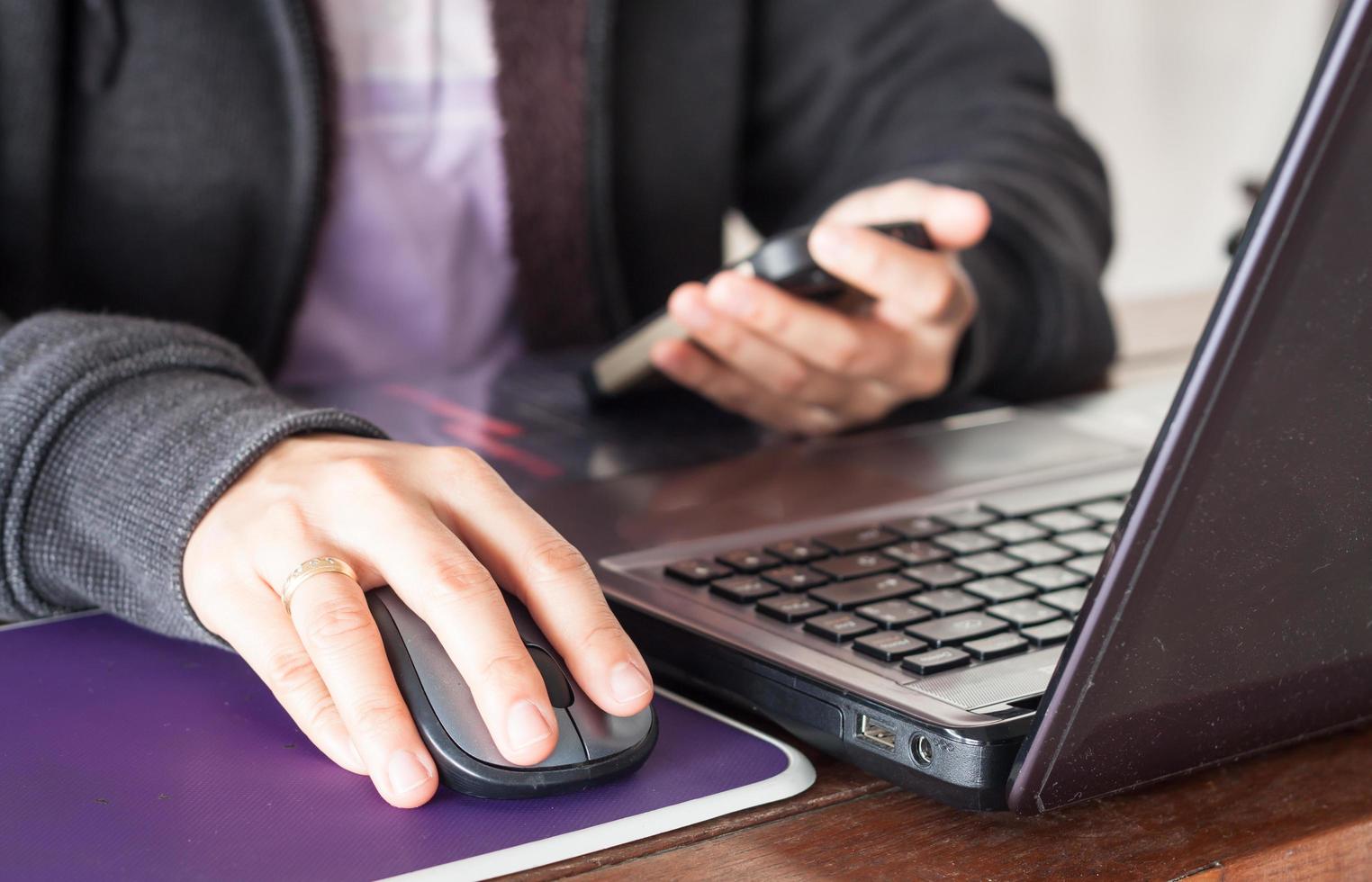 persona che guarda un telefono mentre si lavora su un computer foto