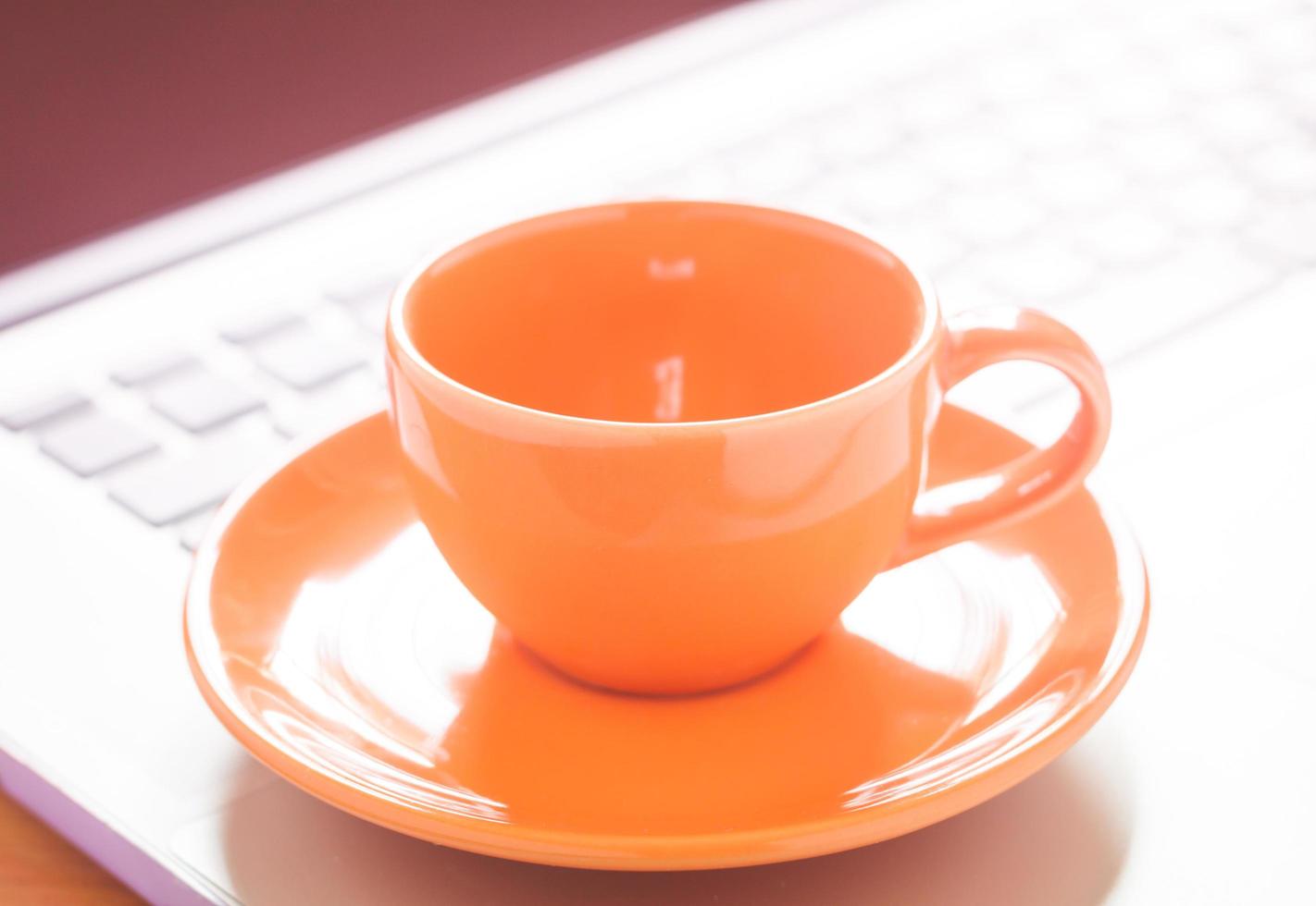 primo piano di una tazza di caffè su un computer portatile foto