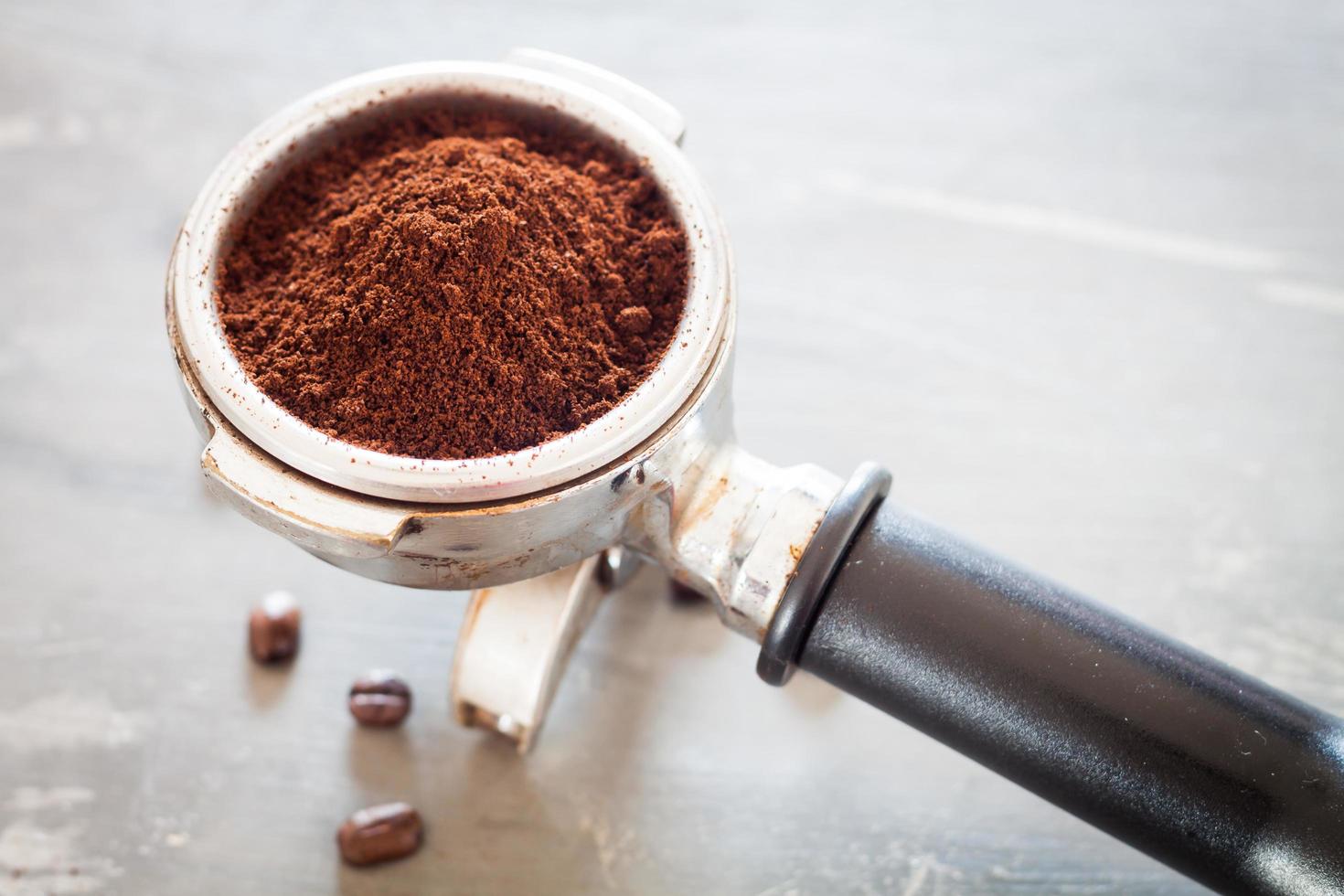 macinino da caffè con chicchi di caffè su un tavolo foto