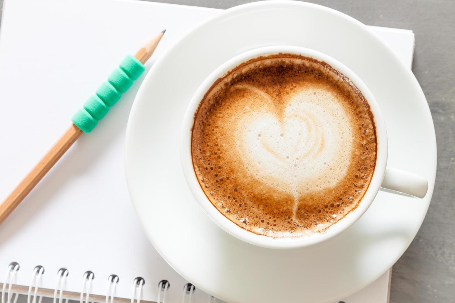 caffè e matita verde su un taccuino foto